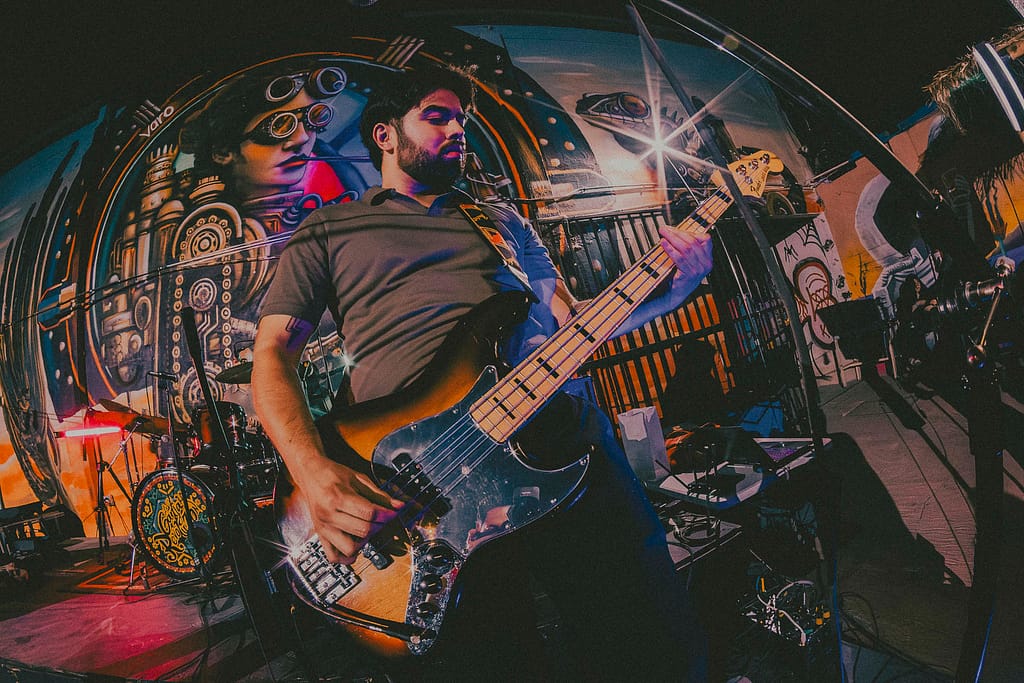 Concierto de Los Martes en vivo en KUP, Mexicali, Baja California. Foto de guitarrista tocando con energía, estilo grunge y estética de revista rockera. Fotografía profesional capturada por Yasunari Murayama con Canon R6, luces cálidas y fondo de mural artístico. Imagen ideal para medios musicales y redes sociales de la banda. Documental de música en vivo, evento cultural en el centro histórico de Mexicali. Rock alternativo, escena independiente, fotografía de espectáculo en vivo, retrato de músico en concierto, ambiente bohemio, estilo visual cinematográfico, fotografía editorial para promoción musical, foto para prensa cultural y agenda de eventos.