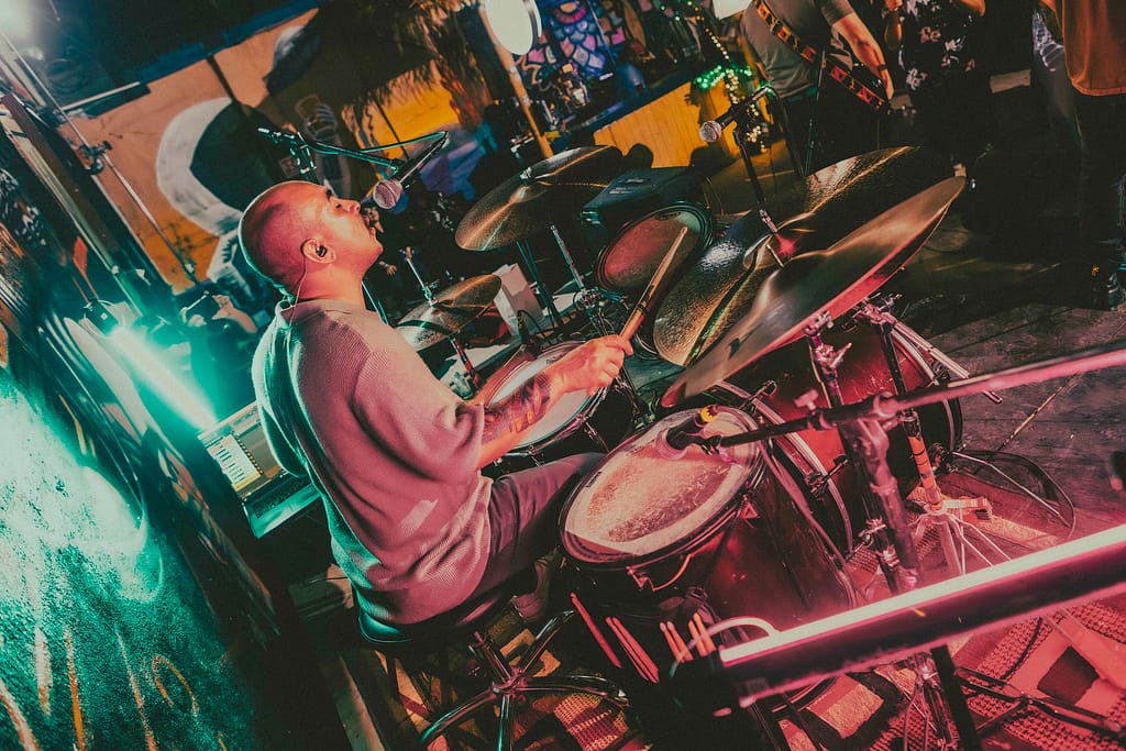 Banda Los Martes interpretando rock alternativo en escenario de KUP, Centro Histórico de Mexicali. Fotografía de alta calidad, estética grunge con influencia editorial, realizada por Yasunari Murayama. Músicos en acción, guitarras eléctricas, batería y bajo. Escena con mural artístico de fondo y luces de concierto. Imagen perfecta para portafolio musical, prensa, y redes de la banda. Evento cultural en Baja California, fotografía artística de rock en vivo, capturas documentales para promoción de grupos independientes. Estilo moderno, colores intensos, fotografía con Canon R6, imagen para cartel de rock, captura de momentos icónicos en el escenario. productor de video en mexicali yasunari murayama