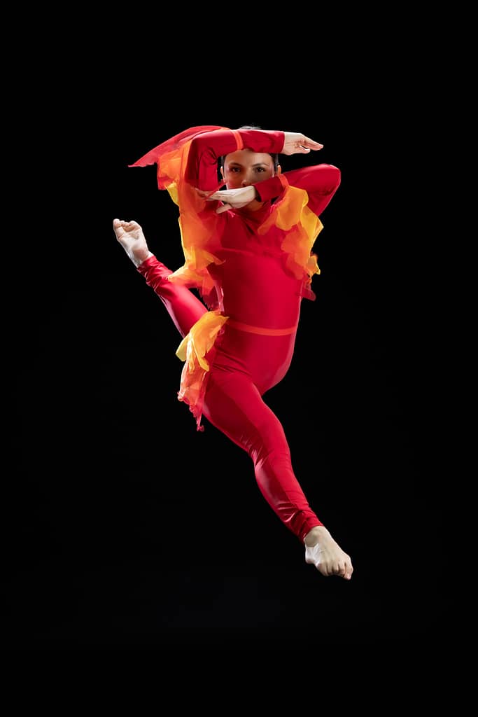 Fotografía profesional de bailarina de Prodanza Mexicali capturada en salto, vestuario rojo y dorado inspirado en Aladdín, fotografía de estudio con fondo negro, alta velocidad y calidad, Mexicali Baja California, producción artística para academias de danza. fotografo y productor de video en mexicali yasunari murayama especialista en efectos especiales