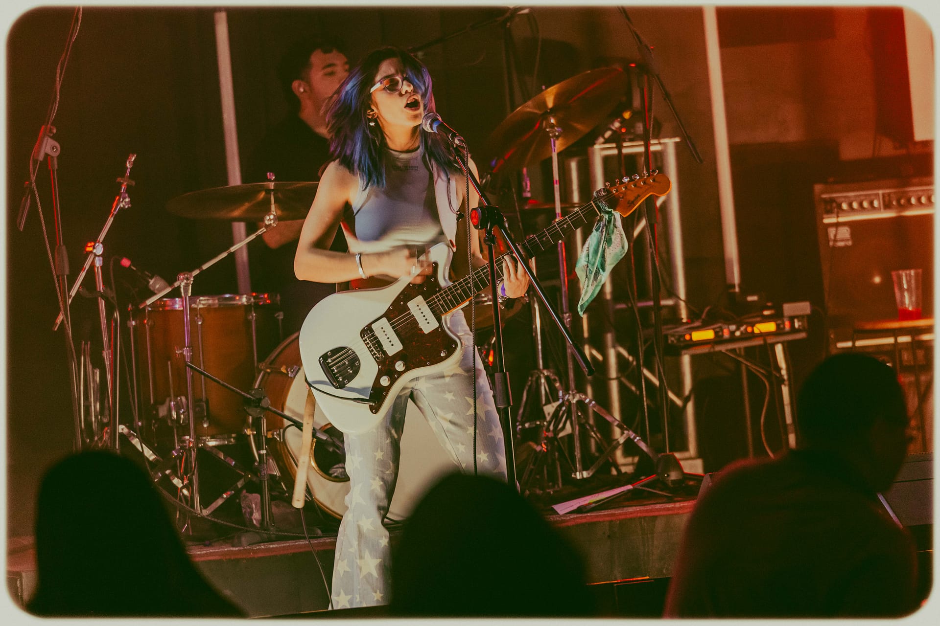 Vocalista Marly MArly con guitarra blanca cantando en el escenario, foto por Yasunari Murayama, productor de fotografía y video en Mexicali. Imagen dinámica de evento musical en foro dragon de Mision Dragon, Fotografía Profesional para Artistas en Vivo Productor de video en mexicali