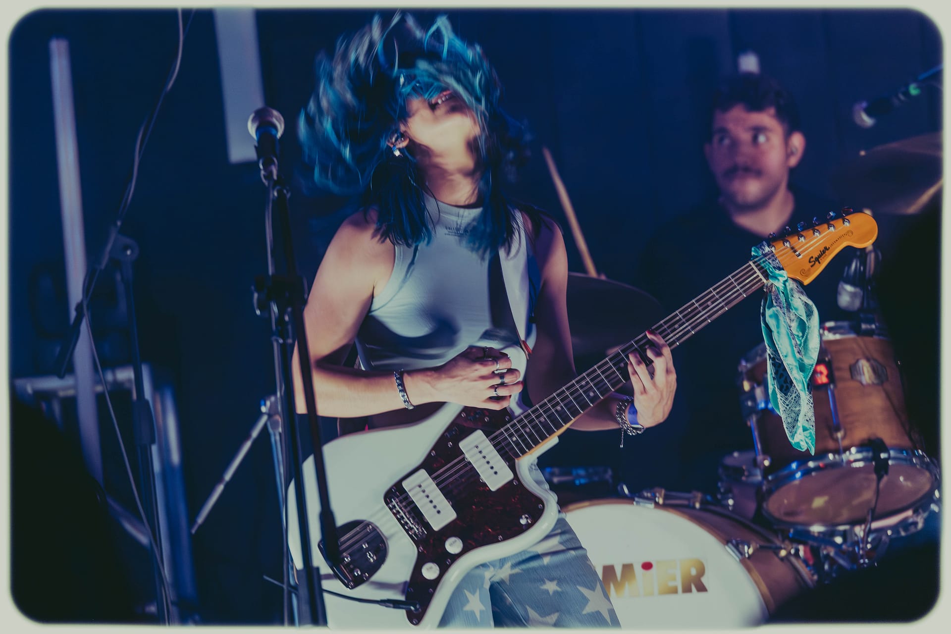 Fotografía artística de guitarrista en movimiento con cabello azul Marly MArly, tomada por Yasunari Murayama, productor de fotografía y video en Mexicali en foro dragon de Mision Dragon, Fotografía Profesional para Artistas en Vivo Productor de video en mexicali